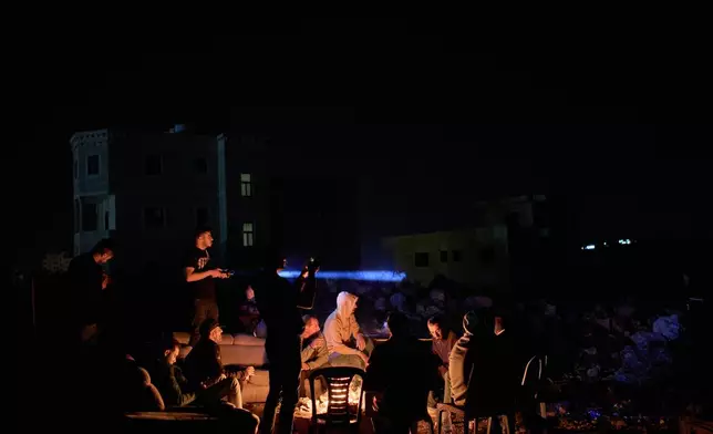 A Palestinian uses a flashlight after spotting the presence of Israeli settlers on a hill as he takes part in a night watch with other volunteers to guard against settler attacks in the West Bank village of Sinjil, Thursday, July 16, 2026. (AP Photo/Leo Correa)
