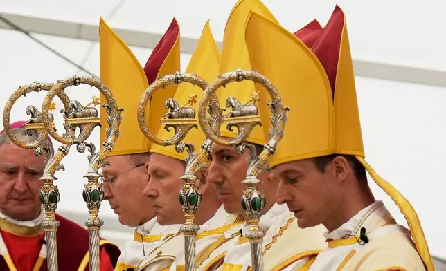 Newly consecrated bishops, from left, Pascal Schreiber, Michael Goldade, Michel Poinsinet de Sivry and Marc Hanappier, wearing their miters and holding their pastoral staffs, pray at the end of their consecration ceremony in a tent set up outside the Society of St. Pius X seminary in Econe, Switzerland, Wednesday, July 1, 2026. (AP Photo/Baz Ratner)