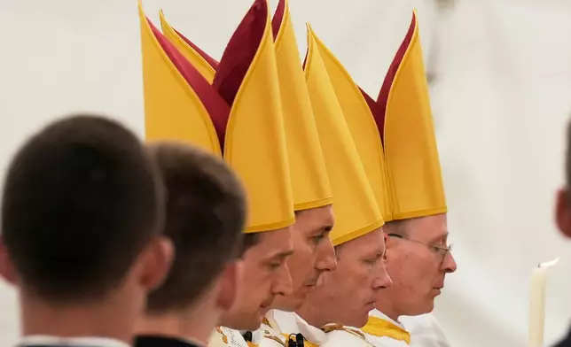Newly consecrated bishops, from left, Marc Hanappier, Michel Poinsinet de Sivry, Michael Goldade and Pascal Schreiber, wearing their miters pray at the end of their consecration ceremony in a tent set up outside the Society of St. Pius X seminary in Econe, Switzerland, Wednesday, July 1, 2026. (AP Photo/Baz Ratner)
