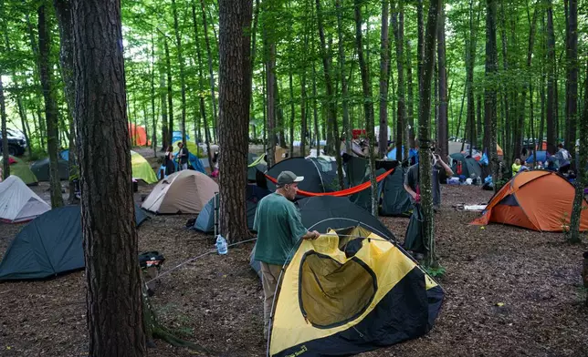 A man installs a tent during the Stoned Climbers festival near Denyshi, Zhytomyr region, Ukraine, Saturday, June 27, 2026. (AP Photo/Evgeniy Maloletka)