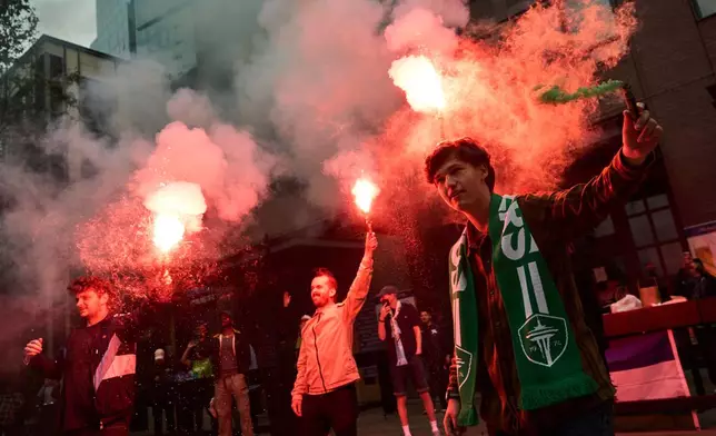 Fans set off flares as Seattle Sounders fans march before an MLS soccer match against the Portland Timbers, Thursday, July 16, 2026, in Seattle. (AP Photo/Lindsey Wasson)