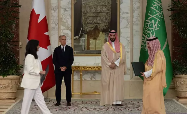 Prime Minister Mark Carney, back left, and Saudi Arabia's Crown Prince Mohammed bin Salman, back right, watch the exchange of documents between Canada's Minister of Foreign Affairs Anita Anand, left, and Saudi Foreign Minister Prince Faisal bin Farhan Al Saud, right, during a signing ceremony at the Royal Palace in Jeddah, Saudi Arabia, Thursday, July 9, 2026. (Adrian Wyld/The Canadian Press via AP)