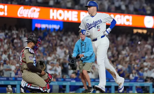 Los Angeles Dodgers' Freddie Freeman, right, scores after hitting a solo home run as San Diego Padres catcher Luis Campusano watches during the sixth inning of a baseball game Saturday, July 4, 2026, in Los Angeles. (AP Photo/Mark J. Terrill)