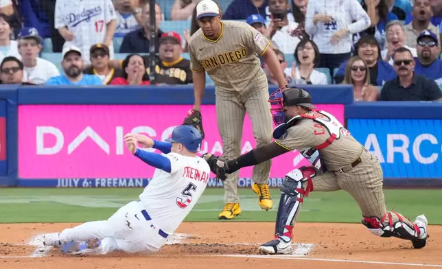 Los Angeles Dodgers' Freddie Freeman, left, is tagged out by San Diego Padres catcher Luis Campusano, right, as he tries to score on a double by Mookie Betts while starting pitcher Wandy Peralta watches during the first inning of a baseball game Saturday, July 4, 2026, in Los Angeles. (AP Photo/Mark J. Terrill)