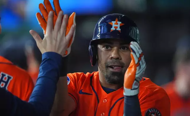 Houston Astros' LaMonte Wade Jr. is congratulated in the dugout after hitting a grand slam during the third inning of a baseball game against the Texas Rangers, Saturday, July 11, 2026, in Arlington, Texas. (AP Photo/LM Otero)