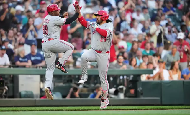 Cincinnati Reds' Eugenio Suárez, right, celebrates his solo home run with third base coach Willie Harris, left, as he runs the bases during the fourth inning of a baseball game against the Seattle Mariners, Tuesday, July 21, 2026, in Seattle. (AP Photo/Lindsey Wasson)