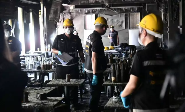 In this handout photo released by Bangkok Metropolitan Administration, forensic police officers inspect the site of a fire in Bangkok, Thailand, Monday, July 13, 2026. (Bangkok Metropolitan Administration via AP)