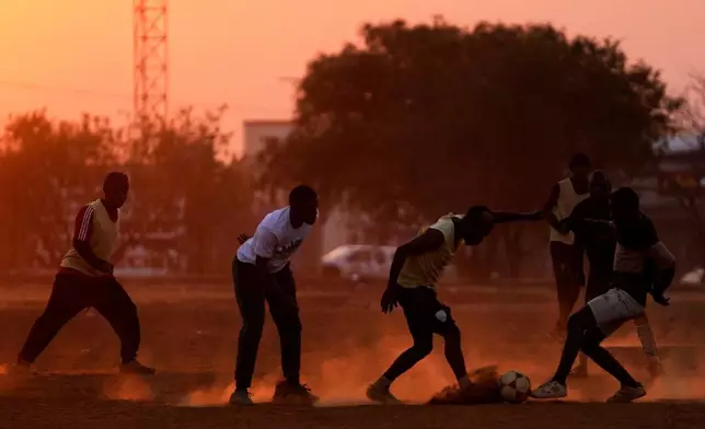 Young men plays soccer on a dusty field, in Soweto, Tuesday, July 7, 2026. (AP Photo/Themba Hadebe)