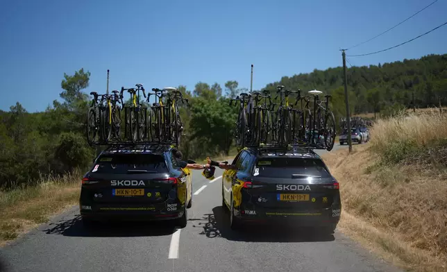 Team cars share equipment during the fourth stage of the Tour de France cycling race over 181.9 kilometers (112.4 miles) with start in Carcassonne and finish in Foix, France, Tuesday, July 7, 2026. (AP Photo/Thibault Camus)