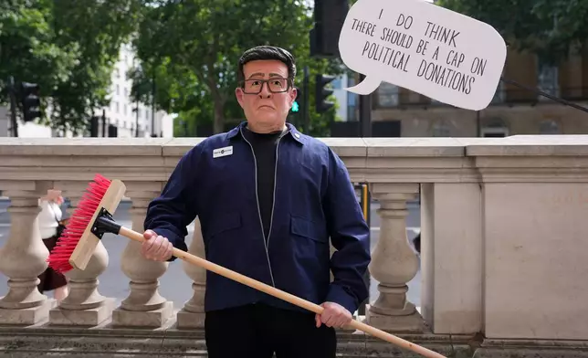 A protester wears a face mask mocking Andy Burnham outside Downing Street as Labour Party leader Andy Burnham is set to become the U.K.'s new prime minister on Monday, succeeding Keir Starmer in London, Monday, July 20, 2026. (AP Photo/Kin Cheung)
