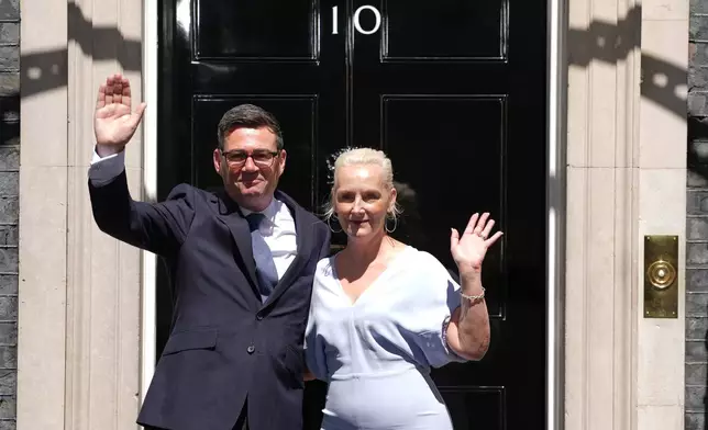 Britain's new Prime Minister Andy Burnham and his wife Marie-France van Heel wave as they arrive at 10 Downing Street in London, Monday, July 20, 2026.(AP Photo/Kirsty Wigglesworth)
