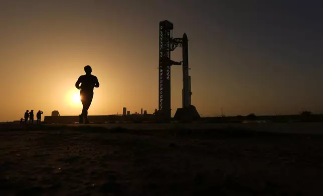 A man jogs past SpaceX's mega rocket Starship as it is prepared for a test flight in Starbase, Texas, Friday, July 24, 2026. (AP Photo/Eric Gay)