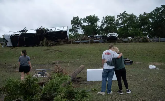 Ryder Wade is comforted by his mother Crystal Wade as they assess flood debris and damage scattered across the Buckhorn Lake Resort RV Park following floods along West Goat Creek near the Guadalupe River on Friday, July 17, 2026, in Kerrville, Texas. (AP Photo/Joel Angel Juarez)