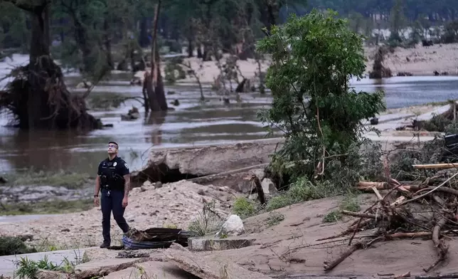 A police officer walks along the Guadalupe River after a series of storms on Friday, July 17, 2026, in Kerrville, Texas. (AP Photo/Gerald Herbert)