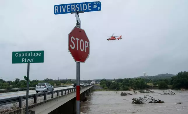 A helicopter flies over the Guadalupe River as floods pass through the area on Thursday, July 16, 2026, in Kerrville, Texas. (AP Photo/Joel Angel Juarez)