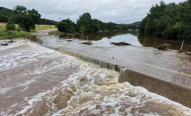The Guadalupe River floods a crossing after a series of storms on Friday, July 17, 2026, in Hunt, Texas. (AP Photo/Gerald Herbert)