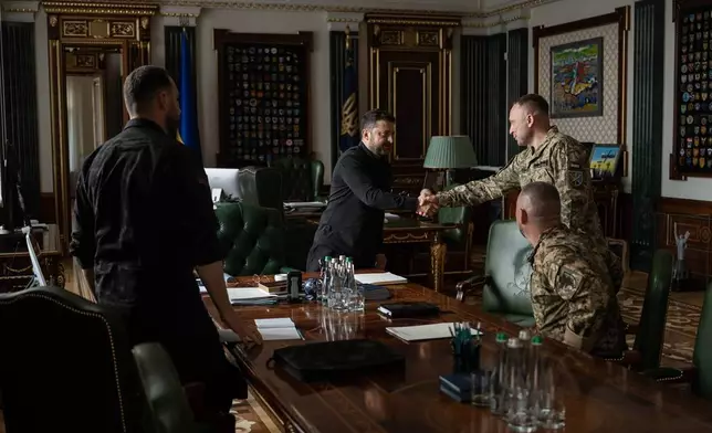 In this photo provided by the Ukrainian Presidential Press Office, Ukrainian President Volodymyr Zelenskyy, center, shakes hands with new commander-in-chief of Ukraine's Armed Forces Mykhailo Drapatyi during their meeting in Kyiv, Ukraine, Monday, July 20, 2026. (Ukrainian Presidential Press Office via AP)
