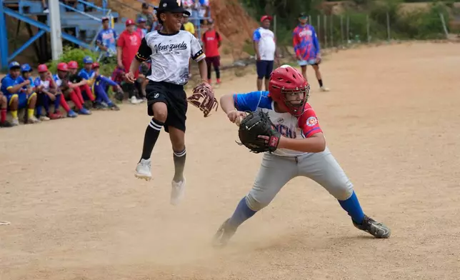 Yeferson Seijas, behind left, whose family lost their home in the earthquakes, plays in a friendly baseball game in La Guaira, Venezuela, Saturday, July 11, 2026. (AP Photo/Ariana Cubillos)