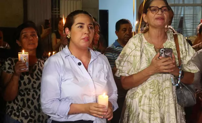 Angie Guerrero, left, sister of Johan Sebastián Durán Guerrero, a Colombian national who was fatally shot by an Immigration and Customs Enforcement officer in Maine, holds a candle during a vigil for her brother at her family home in Bucaramanga, Colombia, Tuesday, July 14, 2026. (AP Photo/Jaime Moreno)