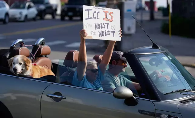 A protester holds a sign as they drive past the scene where a man was shot and killed by U.S. Immigration and Customs Enforcement on Monday, July 13, 2026, in Biddeford, Maine. (AP Photo/Robert F. Bukaty)