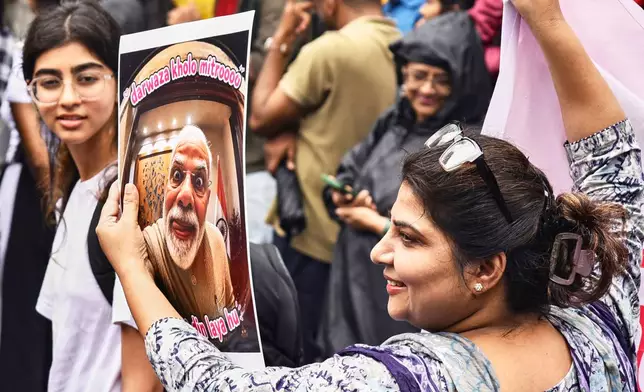 A protestor holds a placard with a portrait of Indian Prime Minister Narendra Modi and the text loosely translated as "Open the Door Friends, I Bring Bad Times" during a demonstration demanding educational reforms as part of the Cockroach Janta Party's ongoing protest movement in Pune, India, Friday, July 24, 2026. (AP Photo)