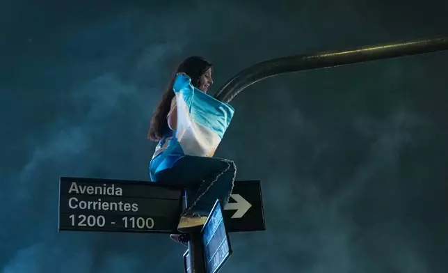 A fan perches atop a traffic signal during celebrations of Argentina's victory over England in a World Cup semifinal soccer match in downtown Buenos Aires, Argentina, Wednesday, July 15, 2026. (AP Photo/Natacha Pisarenko)