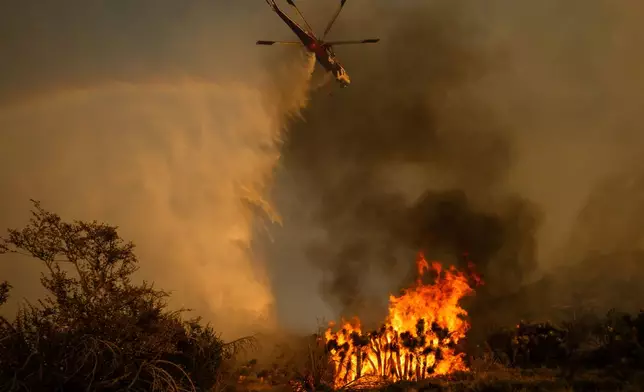 A helicopter drops water on the Summit Fire in Llano, CA. Friday, July 10, 2026. (AP Photo/Ethan Swope)