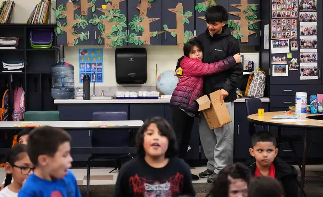 Chief Leschi Schools senior Gerald Dillon, 18, gets a hug from a second grade student as he serves as a teaching assistant through the school's career and technical education program, Wednesday, March 18, 2026, at Chief Leschi Schools in Puyallup, Wash. (AP Photo/Lindsey Wasson)