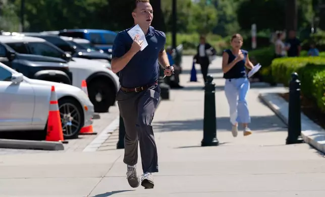 Interns run to deliver documents to the media after a Supreme Court ruling outside the Supreme Court on Capitol Hill, Tuesday, June 30, 2026, in Washington. (AP Photo/Jose Luis Magana)