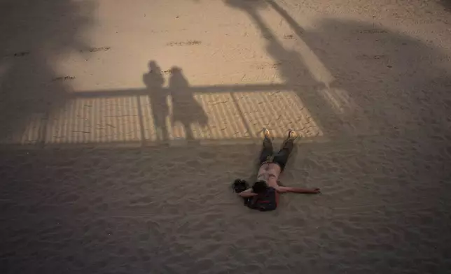 A man sleeps on a beach in Barcelona, Spain, Monday, July 13, 2026. (AP Photo/Emilio Morenatti)