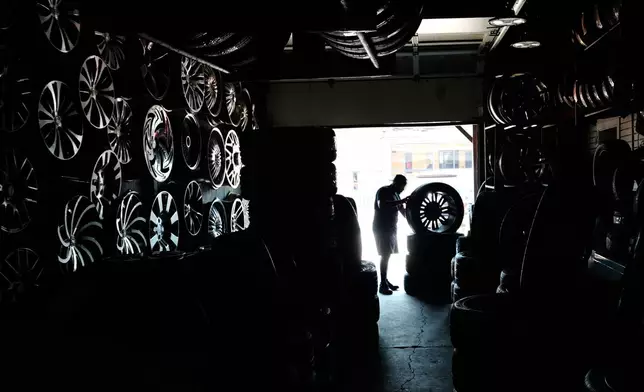 Eric Hood Jr., works on a tire at Hood's Tire Services in the extreme hot weather Tuesday, July 14, 2026, in Detroit. (AP Photo/Paul Sancya)