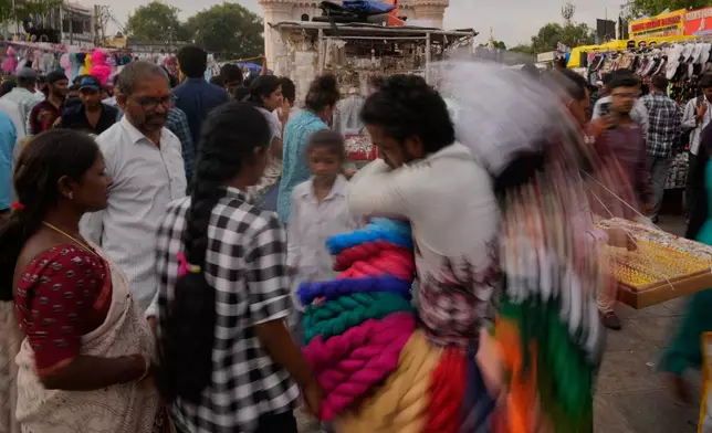 People shop for clothes near the landmark Charminar monument in Hyderabad, India, Saturday, July 11, 2026. (AP Photo/Mahesh Kumar A.)