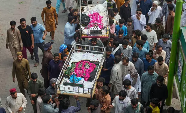 People carry the bodies of children, who were killed in a roof collapse at a tutoring center on the outskirts of Lahore, Pakistan after a funeral prayer Wednesday, July 1, 2026. (AP Photo/K.M. Chaudary)