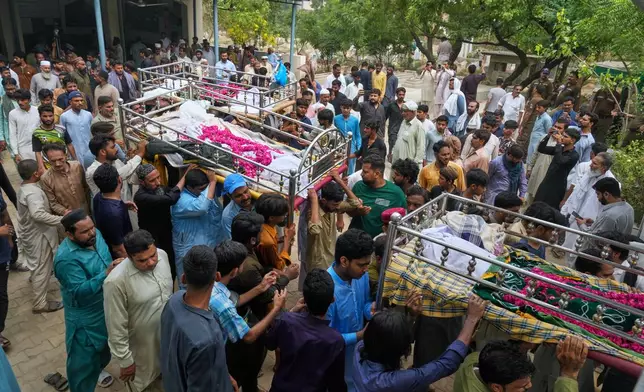 People carry the bodies of children, who were killed in the roof collapse at a tutoring center that was under construction after a funeral prayer, on the outskirts of Lahore, Pakistan, Wednesday, July 1, 2026. (AP Photo/K.M. Chaudary)