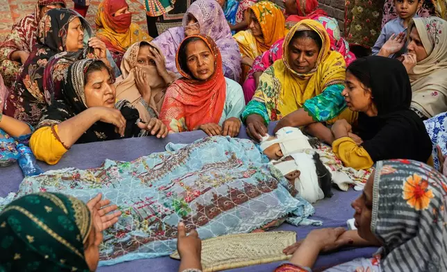 EDS NOTE: GRAPHIC CONTENT - Women mourn around the bodies of their children, who were killed in the roof collapse at a tutoring center that was under construction on the outskirts of Lahore, Pakistan, Wednesday, July 1, 2026. (AP Photo/K.M. Chaudary)
