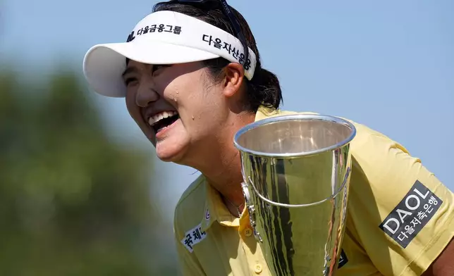 Haeran Ryu, of South Korea, celebrates with her trophy after winning the Evian Championship women's golf tournament, in Evian, eastern France, Sunday, July 12, 2026. (AP Photo/Laurent Cipriani)