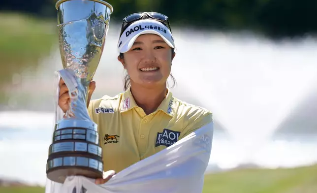 Haeran Ryu, of South Korea, celebrates with her trophy after winning the Evian Championship women's golf tournament, in Evian, eastern France, Sunday, July 12, 2026. (AP Photo/Laurent Cipriani)