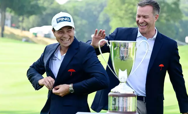 Viktor Hovland, of Norway, reacts as he places the Travelers Championship golf jacket on as tournament director Nathan Grube, right, looks on at TPC River Highlands, Monday, June 29, 2026, in Cromwell, Conn. (AP Photo/Jessica Hill)