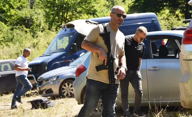 Kosovo policemen guard the site where forensic teams have begun excavations of a mass grave near the village of Kalluder, Wednesday, July 29, 2026. (AP Photo/Florent Bajrami)