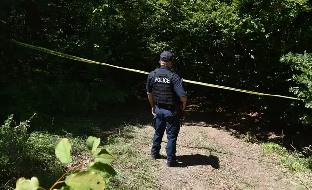 Kosovo policeman guards the site where forensic teams have begun excavations of a mass grave near the village of Kalluder, Wednesday, July 29, 2026. (AP Photo/Florent Bajrami)