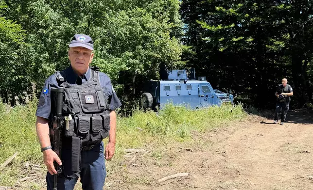 A Kosovo policemen guards the site where forensic teams have begun excavations of a mass grave near the village of Kalluder, Wednesday, July 29, 2026. (AP Photo/Florent Bajrami)