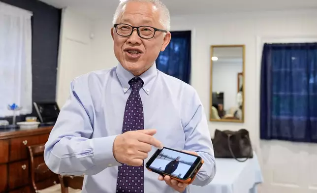 Chinese pastor Ezra Jin Mingri shows his photos after an interview with The Associated Press in Maryland, Wednesday, July 22, 2026 . (AP Photo/Mariam Zuhaib)