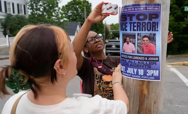 Angeliki Cintron, left, and Saidi Moseley post a notice of an upcoming gathering in response to the recent killings by U.S. Immigration and Customs Enforcement agents, in Biddeford, Maine, Wednesday, July 15 2026. (AP Photo/Robert F. Bukaty)