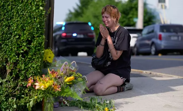 A woman prays after leaving flowers near the scene where a man was shot and killed by U.S. Immigration and Customs Enforcement on Monday, July 13, 2026, in Biddeford, Maine. (AP Photo/Robert F. Bukaty)