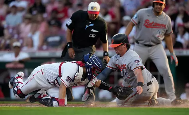 Baltimore Orioles Adley Rutschman, right, is tagged out by Cincinnati Reds catcher Jose Trevino, left, as during the third inning of a baseball game in Cincinnati, Saturday, July 4, 2026. (AP Photo/Carolyn Kaster)