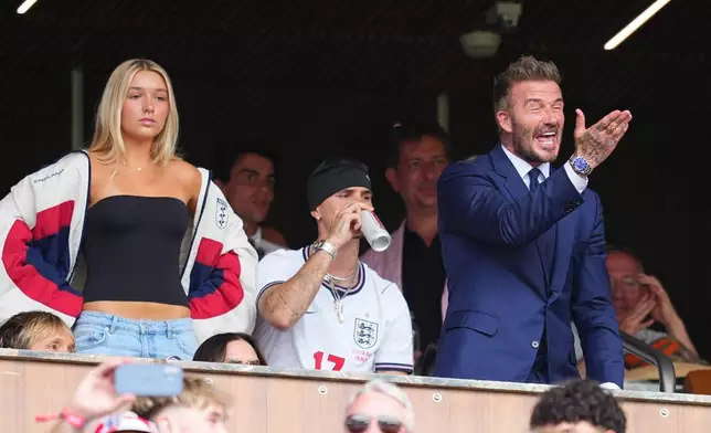 English former soccer player David Beckham gestures from the stands joined by his children, Harper, left, and Romeo ahead of a World Cup quarterfinal soccer match between England and Norway in Miami Gardens, Fla., Saturday, July 11, 2026. (AP Photo/Julio Cortez)