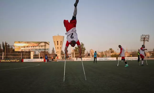 A player balances on his crutches while warming up before the final of Syria's first football tournament for people with disabilities at Al-Muhafaza Stadium in Damascus, Syria, Wednesday, July 29, 2026. (AP Photo/Ghaith Alsayed)