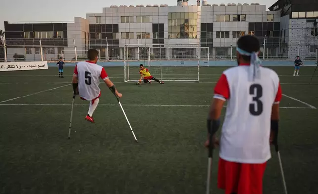 A goalkeeper makes a save as a player takes a shot during warmups before the final of Syria's first football tournament for people with disabilities at Al-Muhafaza Stadium in Damascus, Syria, Wednesday, July 29, 2026. (AP Photo/Ghaith Alsayed)
