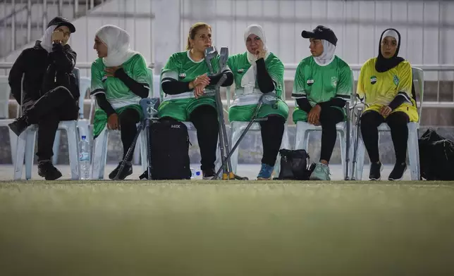 Female players watch the final of Syria's first football tournament for people with disabilities from the sidelines at Al-Muhafaza Stadium in Damascus, Syria, Wednesday, July 29, 2026. (AP Photo/Ghaith Alsayed)
