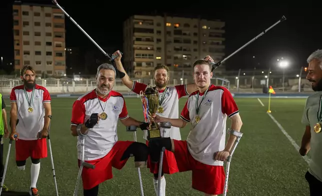 Players from Damascus Governorate Club celebrate with the trophy after defeating Omayya Club in the final of Syria's first football tournament for people with disabilities at Al-Muhafaza Stadium in Damascus, Syria, Wednesday, July 29, 2026. (AP Photo/Ghaith Alsayed)